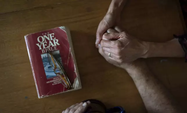 Lesley, right, and Matt Dzik, hold hands as they pray after reading the Bible, Sunday, Sept. 22, 2024, at their home in Champaign, Ill. The couple attend church regularly and when they pray, they hold each other. (AP Photo/David Goldman)