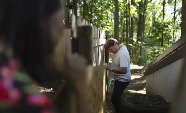 Lesley Dzik, left, helps her husband, Matt, place a sheet of plywood at a renovation job he's doing for a fellow church member in Urbana, Ill., Saturday, Sept. 21, 2024. Acts of kindness bring them together and Matt often does handy-man jobs to help people who can't afford professionals. (AP Photo/David Goldman)