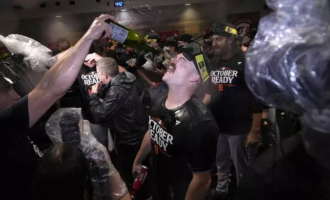 Detroit Tigers catcher Jake Rogers, center, celebrates with the team in the clubhouse after the their 5-2 win against the Houston Astros in Game 2 of an AL Wild Card Series baseball game Wednesday, Oct. 2, 2024, in Houston. (AP Photo/Kevin M. Cox)