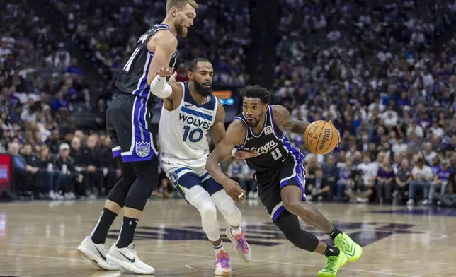 Sacramento Kings guard Malik Monk (0) dribbles past Minnesota Timberwolves guard Mike Conley (10) as Kings forward Domantas Sabonis (11) sets a pick during the first half of an NBA basketball game Thursday, Oct. 24, 2024, in Sacramento, Calif. (AP Photo/Sara Nevis)