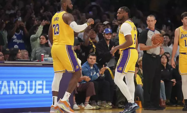 Los Angeles Lakers forward LeBron James (23) and guard Bronny James (9) stand on the court during the first half of an NBA basketball game against the Minnesota Timberwolves, Tuesday, Oct. 22, 2024, in Los Angeles. (AP Photo/Eric Thayer)