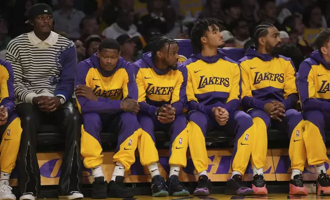 Los Angeles Lakers guard Bronny James, center, watches play from the bench with teammates during the first half of an NBA basketball game against the Minnesota Timberwolves, Tuesday, Oct. 22, 2024, in Los Angeles. (AP Photo/Eric Thayer)