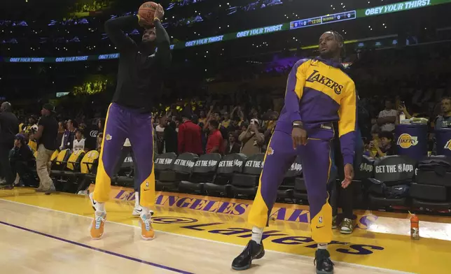 Los Angeles Lakers forward LeBron James, left, and guard Bronny James warm up before an NBA basketball game against the Minnesota Timberwolves, Tuesday, Oct. 22, 2024, in Los Angeles. (AP Photo/Eric Thayer)