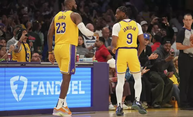 Los Angeles Lakers forward LeBron James (23) and guard Bronny James (9) stand on the court during the first half of an NBA basketball game against the Minnesota Timberwolves, Tuesday, Oct. 22, 2024, in Los Angeles. (AP Photo/Eric Thayer)