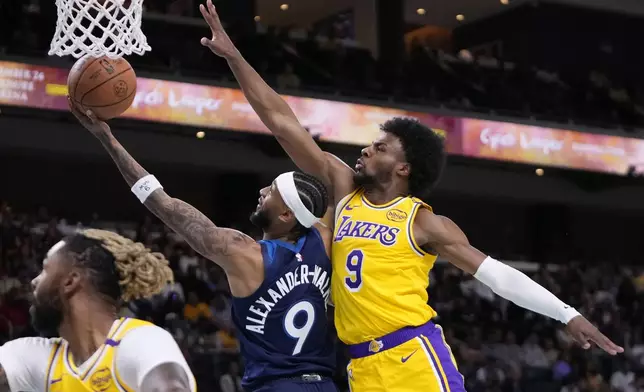 Minnesota Timberwolves guard Nickeil Alexander-Walker, center, shoots as Los Angeles Lakers guard Bronny James, right, defends during the first half of a preseason NBA basketball game, Friday, Oct. 4, 2024, in Palm Desert, Calif. (AP Photo/Mark J. Terrill)