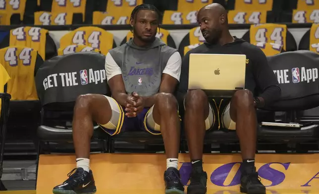 Los Angeles Lakers guard Bronny James, left, sits with a team member before an NBA basketball game against the Minnesota Timberwolves, Tuesday, Oct. 22, 2024, in Los Angeles. (AP Photo/Eric Thayer)