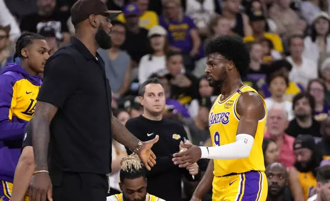 Los Angeles Lakers' LeBron James, left, greets his son, Bronny James as Bronny comes off the court during the first half of a preseason NBA basketball game, Friday, Oct. 4, 2024, in Palm Desert, Calif. (AP Photo/Mark J. Terrill)