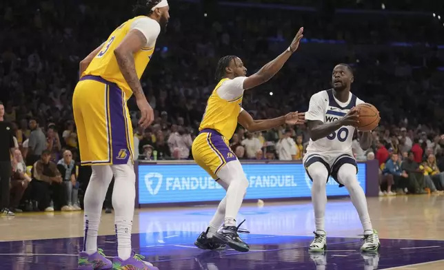 Minnesota Timberwolves forward Julius Randle (30) works toward the basket as Los Angeles Lakers guard Bronny James, center, and forward Anthony Davis defend during the first half of an NBA basketball game, Tuesday, Oct. 22, 2024, in Los Angeles. (AP Photo/Eric Thayer)