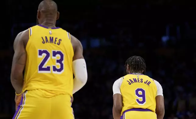 Los Angeles Lakers forward LeBron James (23) and guard Bronny James (9) stand on the court during the first half of an NBA basketball game against the Minnesota Timberwolves, Tuesday, Oct. 22, 2024, in Los Angeles. (AP Photo/Eric Thayer)