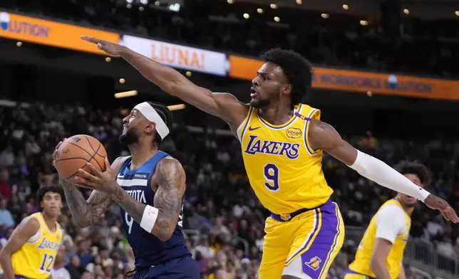 Minnesota Timberwolves guard Nickeil Alexander-Walker, center, shoots as Los Angeles Lakers guard Bronny James, right, defends during the first half of a preseason NBA basketball game, Friday, Oct. 4, 2024, in Palm Desert, Calif. (AP Photo/Mark J. Terrill)