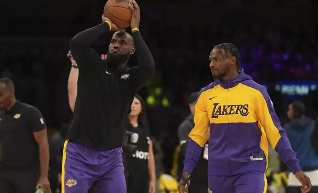 Los Angeles Lakers forward LeBron James, left, and guard Bronny James warm up before an NBA basketball game against the Minnesota Timberwolves, Tuesday, Oct. 22, 2024, in Los Angeles. (AP Photo/Eric Thayer)