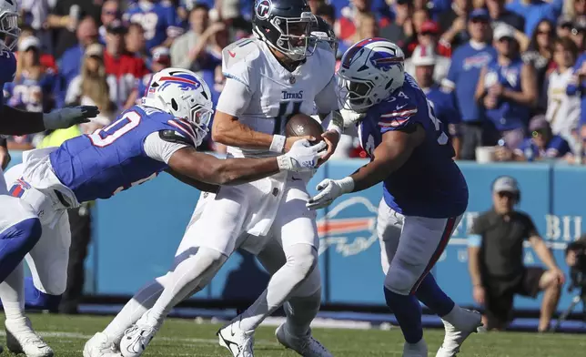 Buffalo Bills defensive end Greg Rousseau, left, and linebacker Baylon Spector (54) sack Tennessee Titans quarterback Mason Rudolph (11) during the second half of an NFL football game Sunday, Oct. 20, 2024, in Orchard Park, N.Y. (AP Photo/Jeffrey T. Barnes)