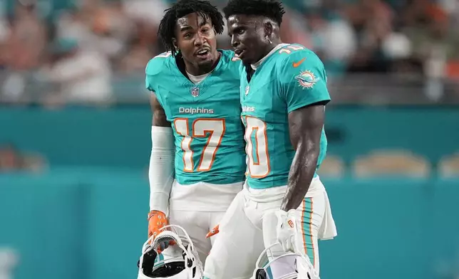 Miami Dolphins wide receiver Jaylen Waddle (17) talks to wide receiver Tyreek Hill (10) during the first half of an NFL football game against the Tennessee Titans, Monday, Sept. 30, 2024, in Miami Gardens, Fla. (AP Photo/Rebecca Blackwell)