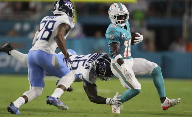 Tennessee Titans linebacker Kenneth Murray Jr. (56) grabs Miami Dolphins wide receiver Tyreek Hill (10) during the first half of an NFL football game, Monday, Sept. 30, 2024, in Miami Gardens, Fla. (AP Photo/Brennan Asplen)