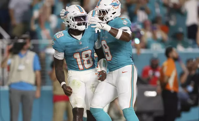 Miami Dolphins quarterback Tyler Huntley (18) celebrates his touchdown with tight end Jonnu Smith (9) during the second half of an NFL football game against the Tennessee Titans, Monday, Sept. 30, 2024, in Miami Gardens, Fla. (AP Photo/Brennan Asplen)