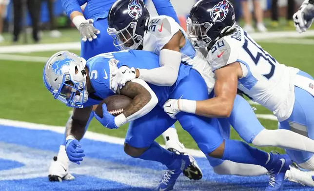 Detroit Lions running back David Montgomery (5) runs into the end zone for a touchdown past Tennessee Titans cornerback Darrell Baker Jr. (39) and linebacker Jack Gibbens (50) during the first half of an NFL football game Sunday, Oct. 27, 2024, in Detroit. (AP Photo/Paul Sancya)