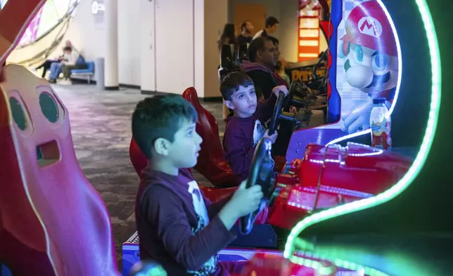 Twins Josh and Zach Alli, 6, of Toronto play racing games at The Strong National Museum of Play, Tuesday, Oct. 15, 2024, in Rochester, N.Y. (AP Photo/Lauren Petracca)