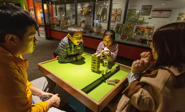 Jesse and Lydia Xu of Toronto play a game of Jenga with their kids Casper, 9, and Lydia, 8, at The Strong National Museum of Play, Tuesday, Oct. 15, 2024, in Rochester, N.Y. (AP Photo/Lauren Petracca)