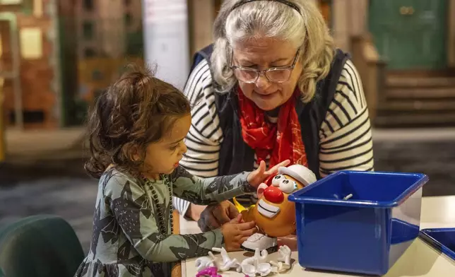 Suellen Sues puts together a Potato Head with her granddaughter, Isla, 2, while visiting The Strong National Museum of Play, Tuesday, Oct. 15, 2024, in Rochester, N.Y. (AP Photo/Lauren Petracca)