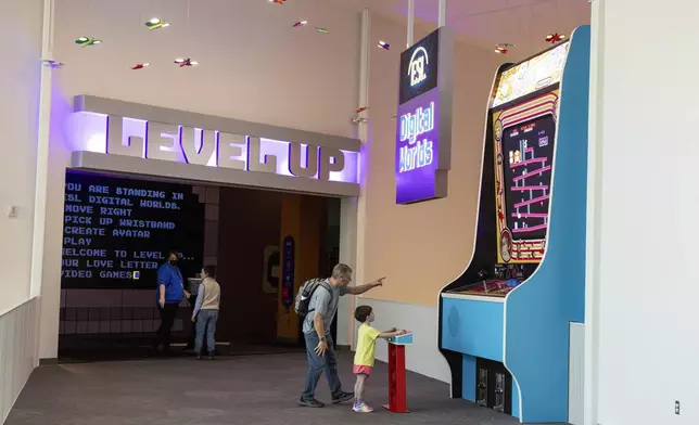 Travis Skadberg watches as Jacob, 6, plays a giant game of Donkey Kong at The Strong National Museum of Play, Tuesday, Oct. 15, 2024, in Rochester, N.Y. (AP Photo/Lauren Petracca)