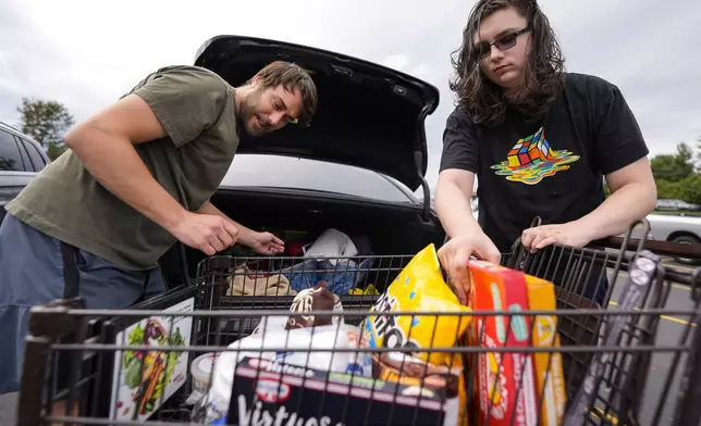 Drew Merritt, left, and Jeremy King load groceries after standing in line outside an Ingles grocery store in the aftermath of Hurricane Helene, Monday, Sept. 30, 2024, in Asheville, N.C. (AP Photo/Mike Stewart)