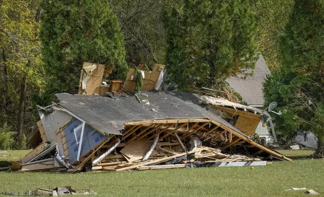 One of the homes belonging to the White family rests on its side in the aftermath of Hurricane Helene, Tuesday, Oct. 1, 2024 in Morganton, N.C. The adjacent Catawba River flooded due to torrential rains destroying seven of the family's nine homes on the property. (AP Photo/Kathy Kmonicek)