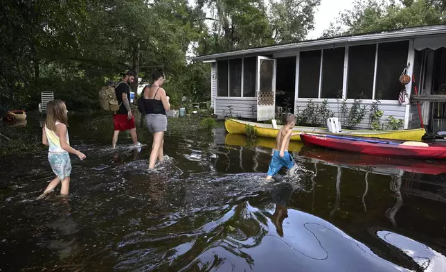 FILE - Dustin Holmes, rear, his girlfriend Hailey Morgan, and her children Aria Skye Hall, 7, left, and Kyle Ross, 4, right, arrive to their flooded home in the aftermath of Hurricane Helene, Sept. 27, 2024, in Crystal River, Fla. (AP Photo/Phelan M. Ebenhack, File)