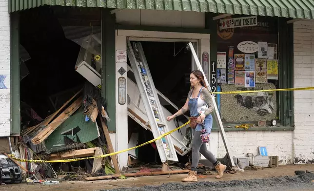 A person walks past a building heavily damaged during Hurricane Helene Tuesday, Oct. 1, 2024, in Hot Springs, N.C. (AP Photo/Jeff Roberson)