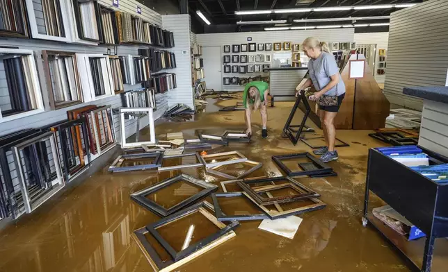 Employees Linda Bandy, left, and Carissa Sheehan clean up International Moulding frame shop damaged by flood water from Hurricane Helene on North Green Street, Monday, Sept. 30, 2024, in Morganton, N.C. (AP Photo/Kathy Kmonicek)