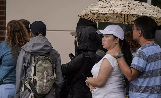 People wait to buy groceries as they stand in line outside an Ingles grocery store in the aftermath of Hurricane Helene, Monday, Sept. 30, 2024, in Asheville, N.C. (AP Photo/Mike Stewart)