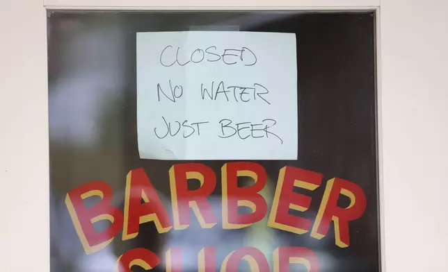 A sign hangs outside a closed barber shop and bar in Asheville, N.C., Monday, Sept. 30, 2024. (AP Photo/Jeffrey Collins)