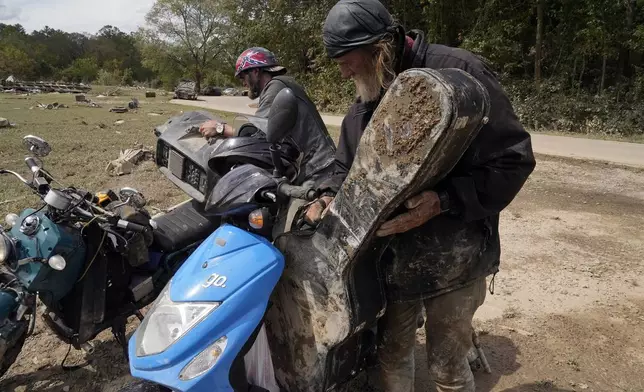 Friends Robert Smith and David Mayben salvage items from the home of a family member who passed away in flooding, Tuesday, Oct. 1, 2024 in Hendersonville, N.C., in the aftermath of Hurricane Helene. (AP Photo/Brittany Peterson)