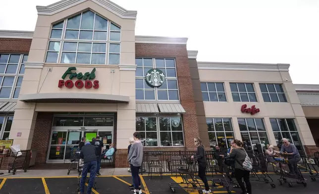 People wait to buy groceries as they stand in line outside an Ingles grocery store in the aftermath of Hurricane Helene, Monday, Sept. 30, 2024, in Asheville, N.C. (AP Photo/Mike Stewart)
