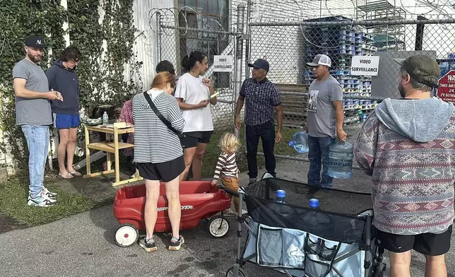 People wait to gather water at Mountain Valley Water in the aftermath of Hurricane Helene in West Asheville, N.C., Monday, Sept. 30, 2024. (AP Photo/Jeffrey Collins)