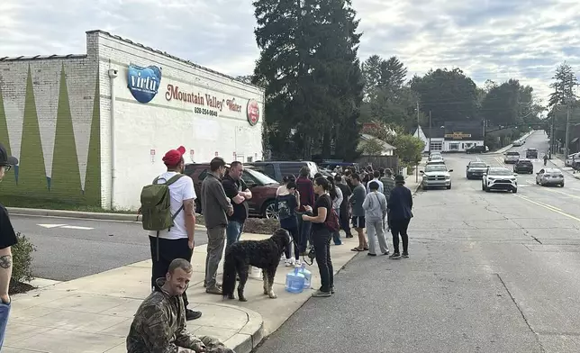 People wait to gather water at Mountain Valley Water in the aftermath of Hurricane Helene in West Asheville, N.C., Monday, Sept. 30, 2024. (AP Photo/Jeffrey Collins)