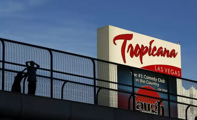 FILE - People stand on a pedestrian bridge by the Tropicana hotel and casino, Aug. 4, 2015, in Las Vegas. (AP Photo/John Locher, File)