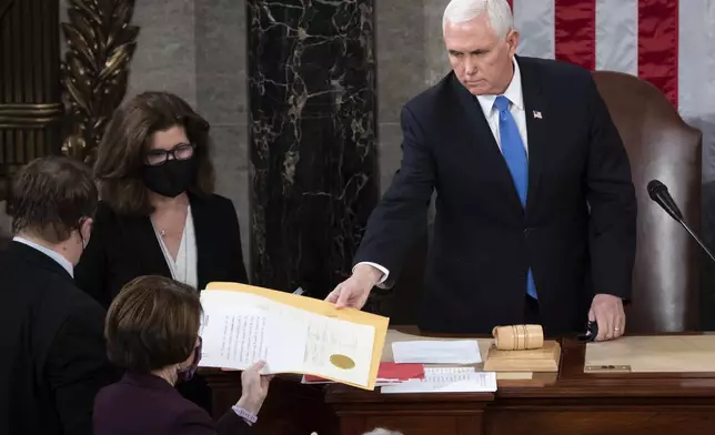 FILE - Vice President Mike Pence hands the electoral certificate from the state of Arizona to Sen. Amy Klobuchar, D-Minn., as he presides over a joint session of Congress as it convenes to count the Electoral College votes cast in November's election, at the Capitol in Washington, Jan. 6, 2021. (Saul Loeb/Pool via AP, File)