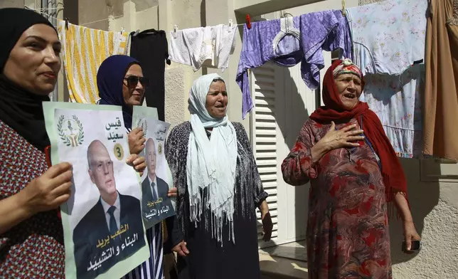 Supporters of Tunisian President and candidate for re-election Kais Saied meet with residents of a neighbourhood during a campaign tour, in Ariana, Tunisia, Thursday, Sept. 26, 2024. (AP Photo/Anis Mili)