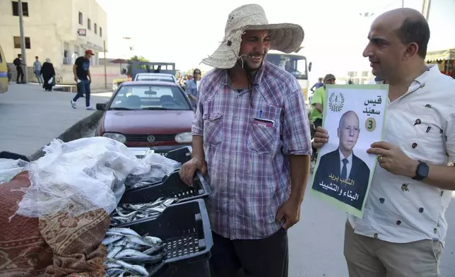 A supporter of Tunisian President and candidate for re-election Kais Saied meets with residents of a neighbourhood during a campaign tour, in Ariana, Tunisia, Thursday, Sept. 26, 2024. (AP Photo/Anis Mili)