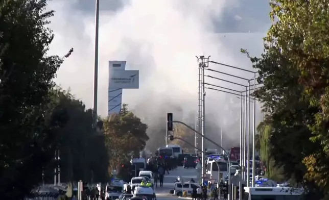 Smoke raises as emergency rescue teams and police officers attend outside Turkish Aerospace Industries Inc. on the outskirts of Ankara, Turkey, Wednesday, Oct. 23, 2024. (IHA via AP)