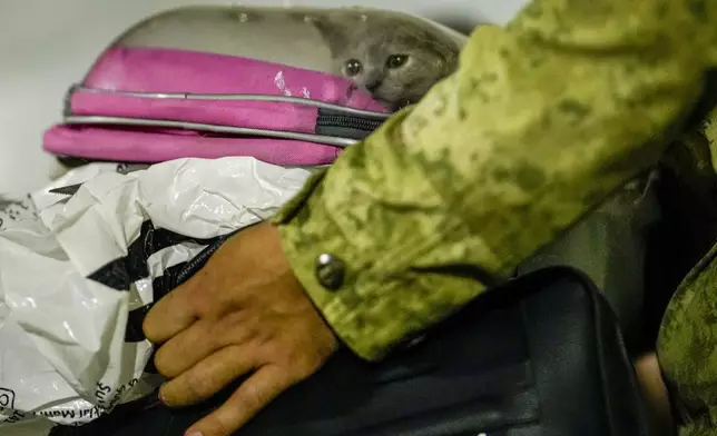 A Turkish military member carries luggages as people mostly Turkish nationals disembark from Turkish TCG Sancaktar military ship after being evacuated from Lebanon's capital Beirut to Turkey, in Mersin port, southern Turkey, early Friday, Oct. 11, 2024. (AP Photo/Emrah Gurel)