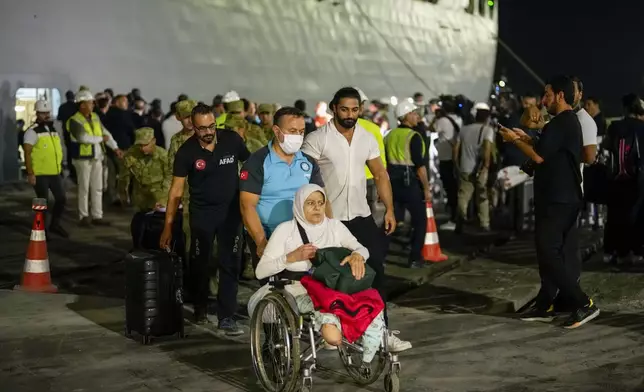 People, mostly Turkish nationals, disembark from Turkish TCG Sancaktar military ship after being evacuated from Lebanon's capital Beirut to Turkey, in Mersin port, southern Turkey, early Friday, Oct. 11, 2024. (AP Photo/Emrah Gurel)