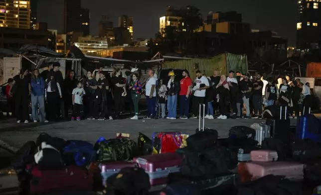 Turkish citizens stand in line waiting for their turn to board two Turkish military ships to evacuate them from Lebanon to Turkey, in Beirut port, Wednesday, Oct. 9, 2024. (AP Photo/Emrah Gurel)