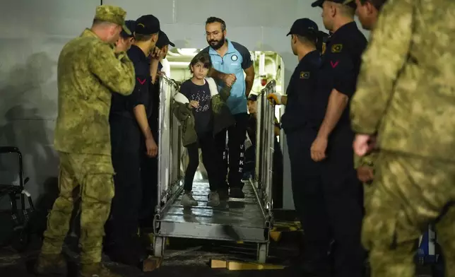 People, mostly Turkish nationals, disembark from Turkish TCG Sancaktar military ship after being evacuated from Lebanon's capital Beirut to Turkey, in Mersin port, southern Turkey, early Friday, Oct. 11, 2024. (AP Photo/Emrah Gurel)