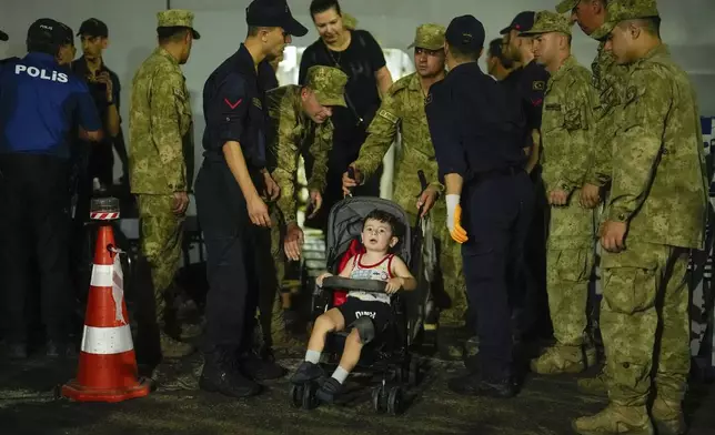 Emergency teams and military personnel help people, mostly Turkish nationals, to disembark from Turkish TCG Sancaktar military ship after being evacuated from Lebanon's capital Beirut to Turkey, in Mersin port, southern Turkey, early Friday, Oct. 11, 2024. (AP Photo/Emrah Gurel)