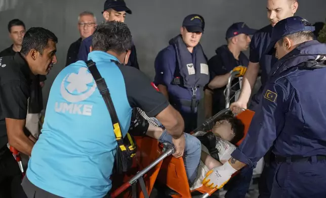 Emergency teams and military personnel help people mostly Turkish nationals to disembark from a Turkish TCG Sancaktar military ship after being evacuated from Lebanon's capital Beirut to Turkey, in Mersin port, southern Turkey, early Friday, Oct. 11, 2024. (AP Photo/Emrah Gurel)