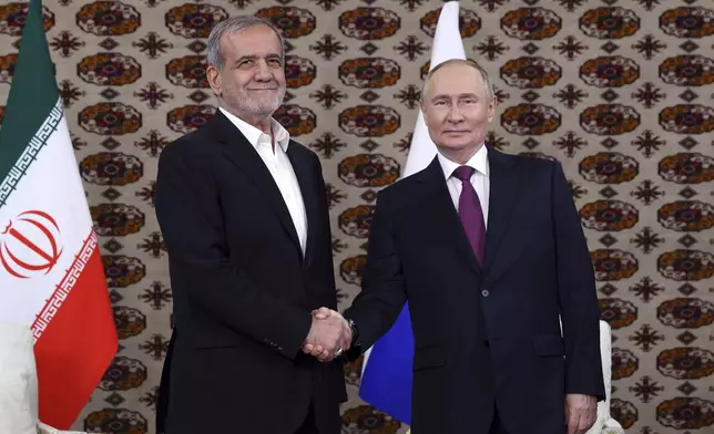 Russian President Vladimir Putin, right, and Iranian President Masoud Pezeshkian shake hands during their meeting on the sidelines of the International Forum "The Interconnection of Times and Civilizations – the basis of peace and development" dedicated to the 300th anniversary of the birth of the outstanding Turkmen poet and thinker Magtymguly Fragi in Ashgabat, Turkmenistan, Friday, Oct. 11, 2024. (Alexander Shcherbak, Sputnik, Kremlin Pool Photo via AP)