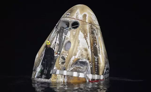 This photo provided by NASA shows a member of the support team as they work around the SpaceX Dragon Endeavour spacecraft shortly after it landed, in the Gulf of Mexico off the coast of Pensacola, Florida, Friday, Oct. 25, 2024. (NASA/Joel Kowsky via AP)