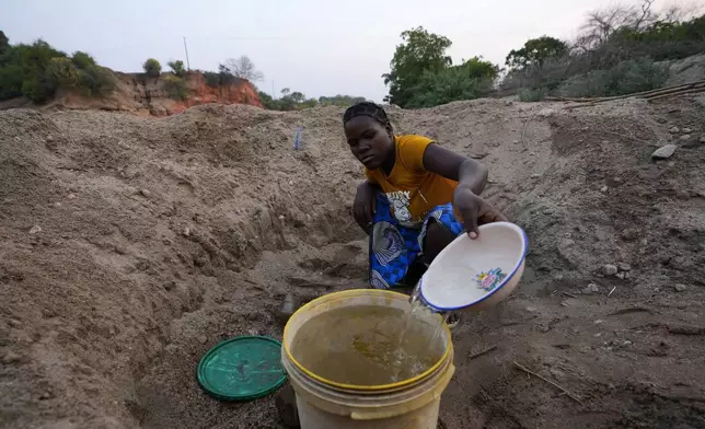 File — A woman scoops water from a hole she has dug in a dried up riverbed in Lusitu, Zambia, Wednesday, Sept. 18, 2024. (AP Photo/Themba Hadebe/File)