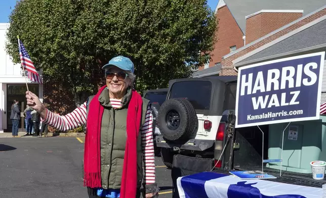 Outside the Rutherford County Annex Building where early voting is taking place, Susan McGowan waves a United States flag in support of Vice President Kamala Harris and Governor Tim Walz, Thursday, October 17, 2024 in Rutherfordton, N.C. (AP Photo/Kathy Kmonicek)